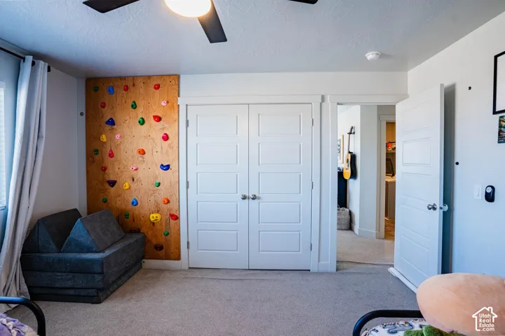 Recessed lighting with a ceiling fan, light-toned carpeting, and a built-in climbing wall feature