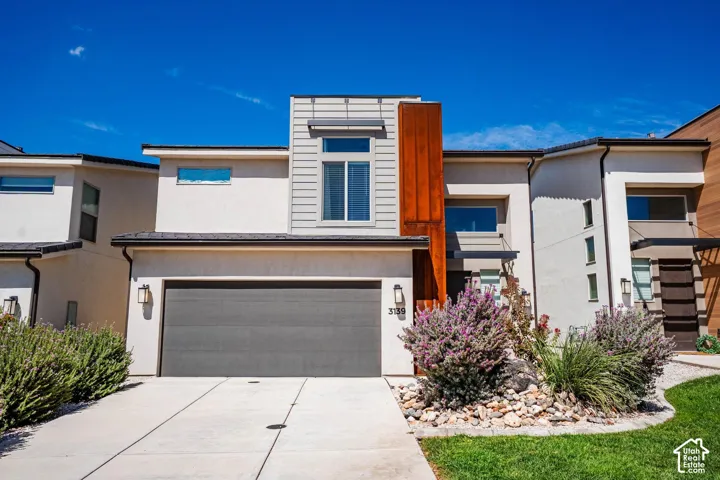 Modern exterior with a neutral stucco finish, vertical wood-look siding, a dark garage door, and a concrete driveway