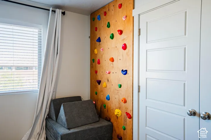 Built-in climbing wall with colorful holds, white paneled doors, and a window with horizontal blinds