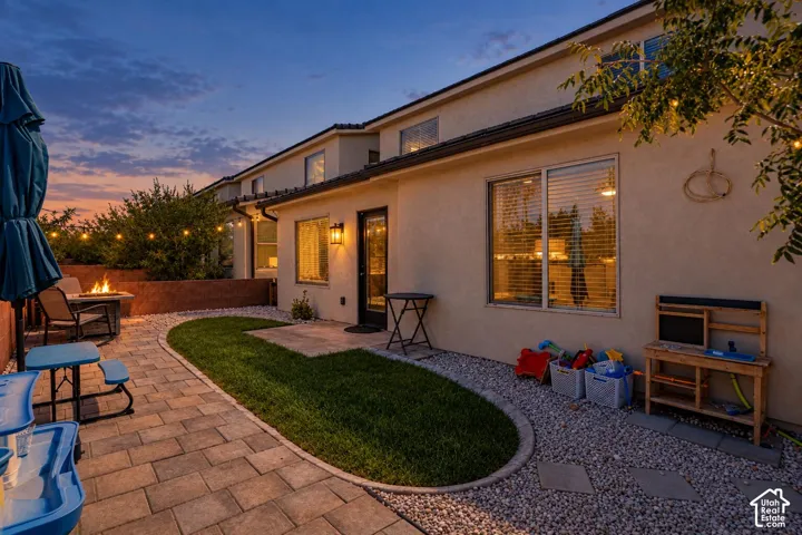 Private patio with paver stones, a fire pit, and a stucco exterior