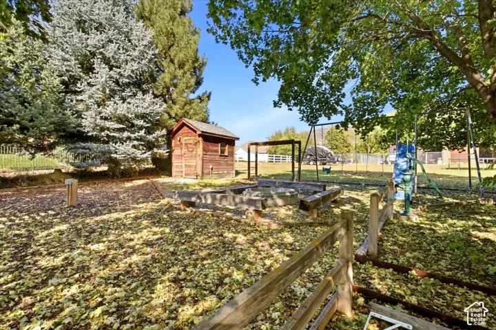 Expansive exterior featuring mature trees, a wooden shed, raised garden beds, and a wood split-rail fence