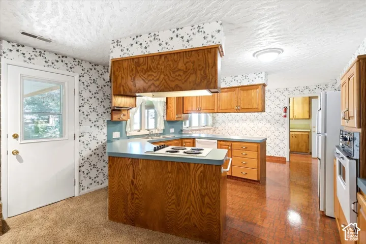 Spacious kitchen featuring rich wood cabinetry, stainless steel appliances, a central island with wood-finish countertop, decorative tile backsplash, and wood-finish flooring throughout the open layout