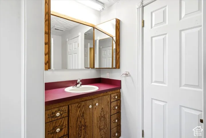 Wood-finish vanity with an integrated basin sink, countertop, and wood-framed mirrored medicine cabinet