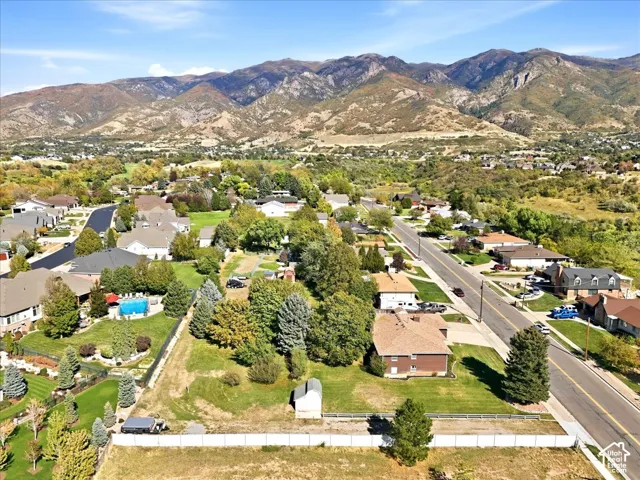 Residential neighborhood featuring mature trees, paved roads, and distant mountain scenery