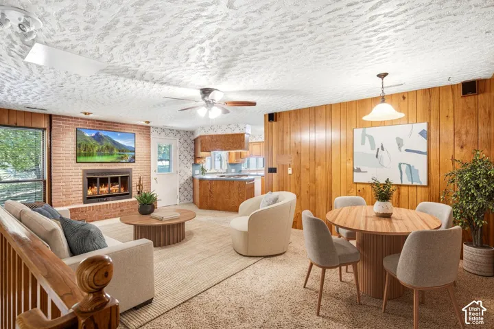 Brick fireplace with an integrated firebox, wood-paneled accent wall, and a ceiling-mounted fan fixture
