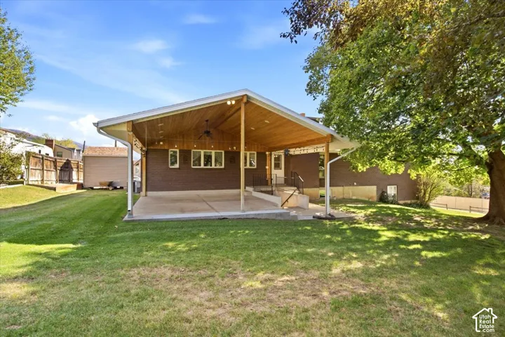 Expansive backyard featuring a covered patio with wood-paneled ceiling, ceiling fan, and recessed lighting