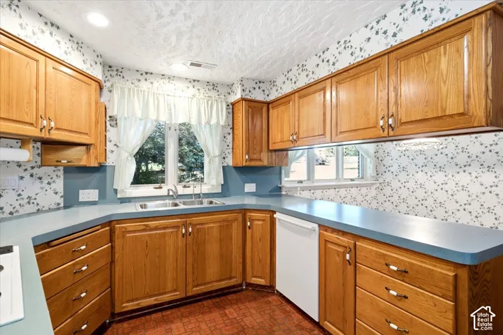Kitchen featuring wood-finish cabinetry, a double basin stainless steel sink, and a built-in dishwasher