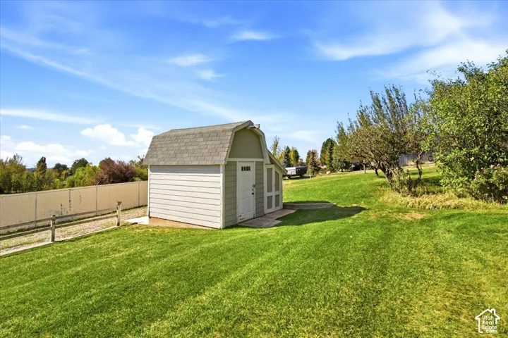Expansive green lawn with a detached storage shed featuring a gambrel roof and a paneled door