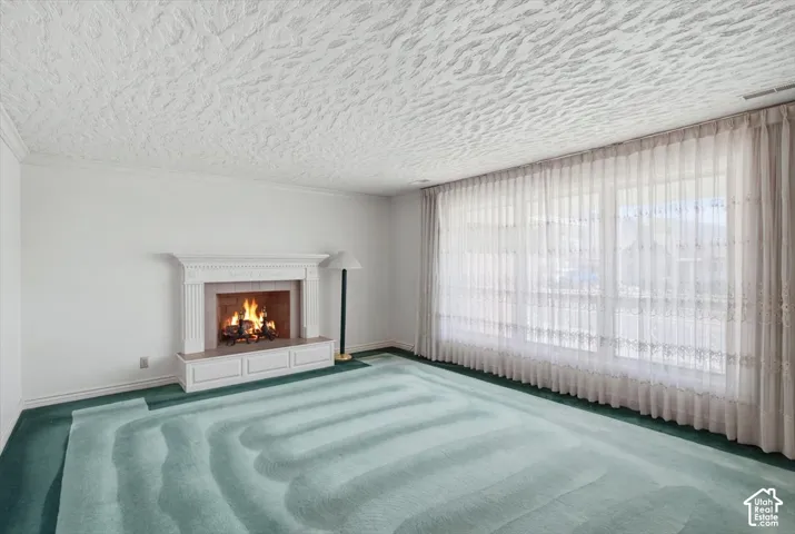 Built-in fireplace with a decorative mantle, full wall of windows, and textured ceiling