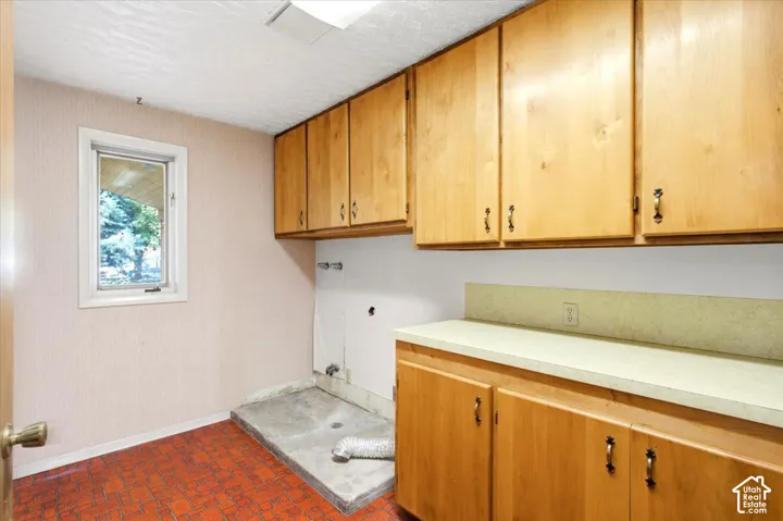 Light wood-finish cabinetry providing ample storage, a durable countertop, and a single window