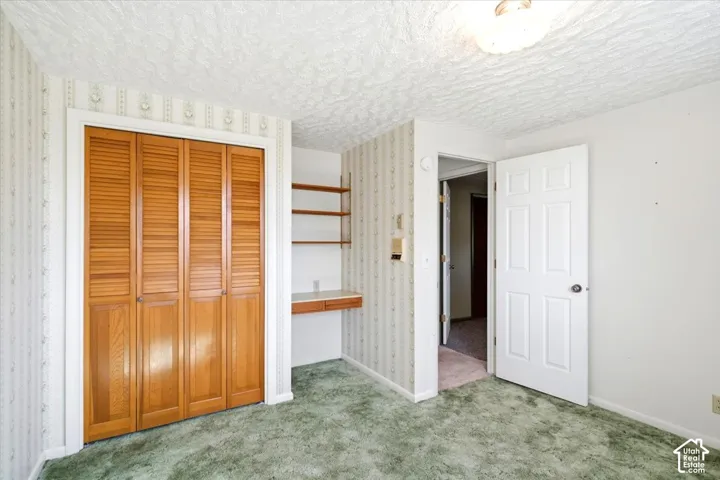 Wood-finish bi-fold closet doors, built-in desk with shelving, and overhead flush-mount lighting