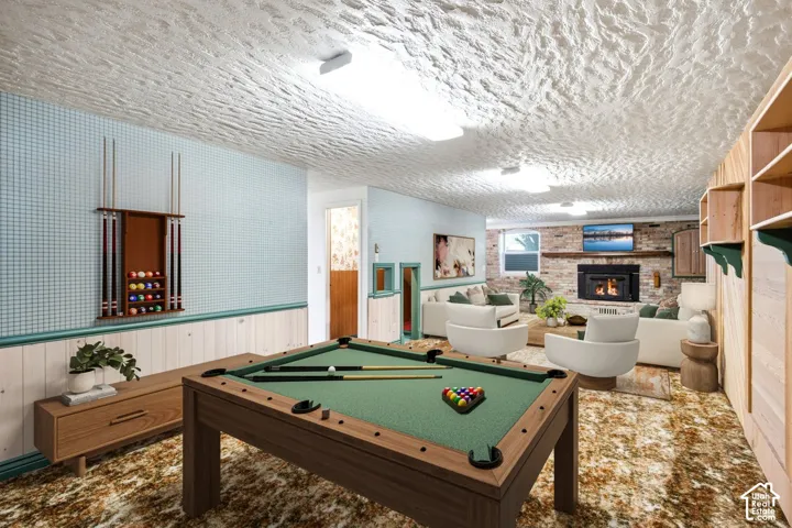 Recreation room featuring a built-in fireplace with a brick surround, wood-finish shelving, and a wood-finish wainscoting