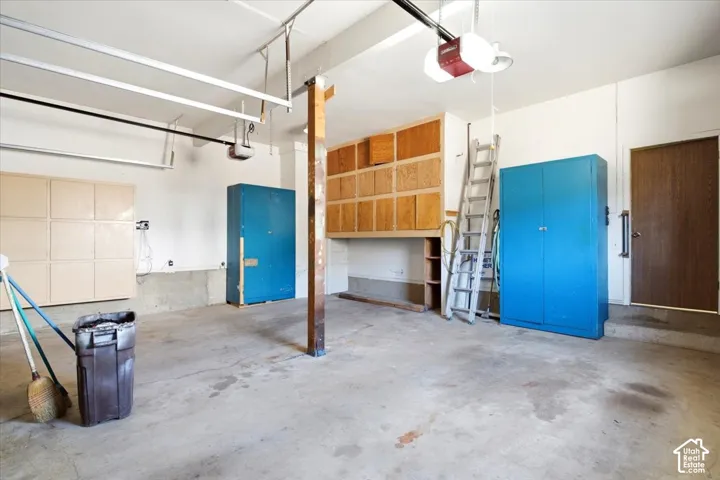 Spacious garage featuring concrete flooring, built-in overhead wooden cabinetry, and an automatic garage door opener