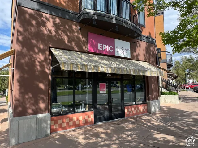Ground-level commercial storefront featuring a striped awning, large display windows, and a tiled facade