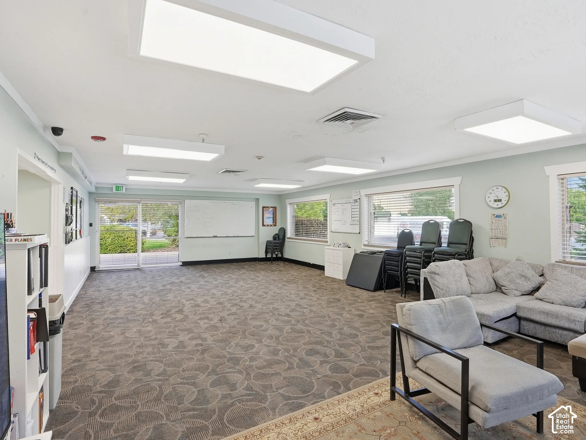 Expansive open area featuring patterned carpet flooring, multiple large windows, and recessed lighting fixtures