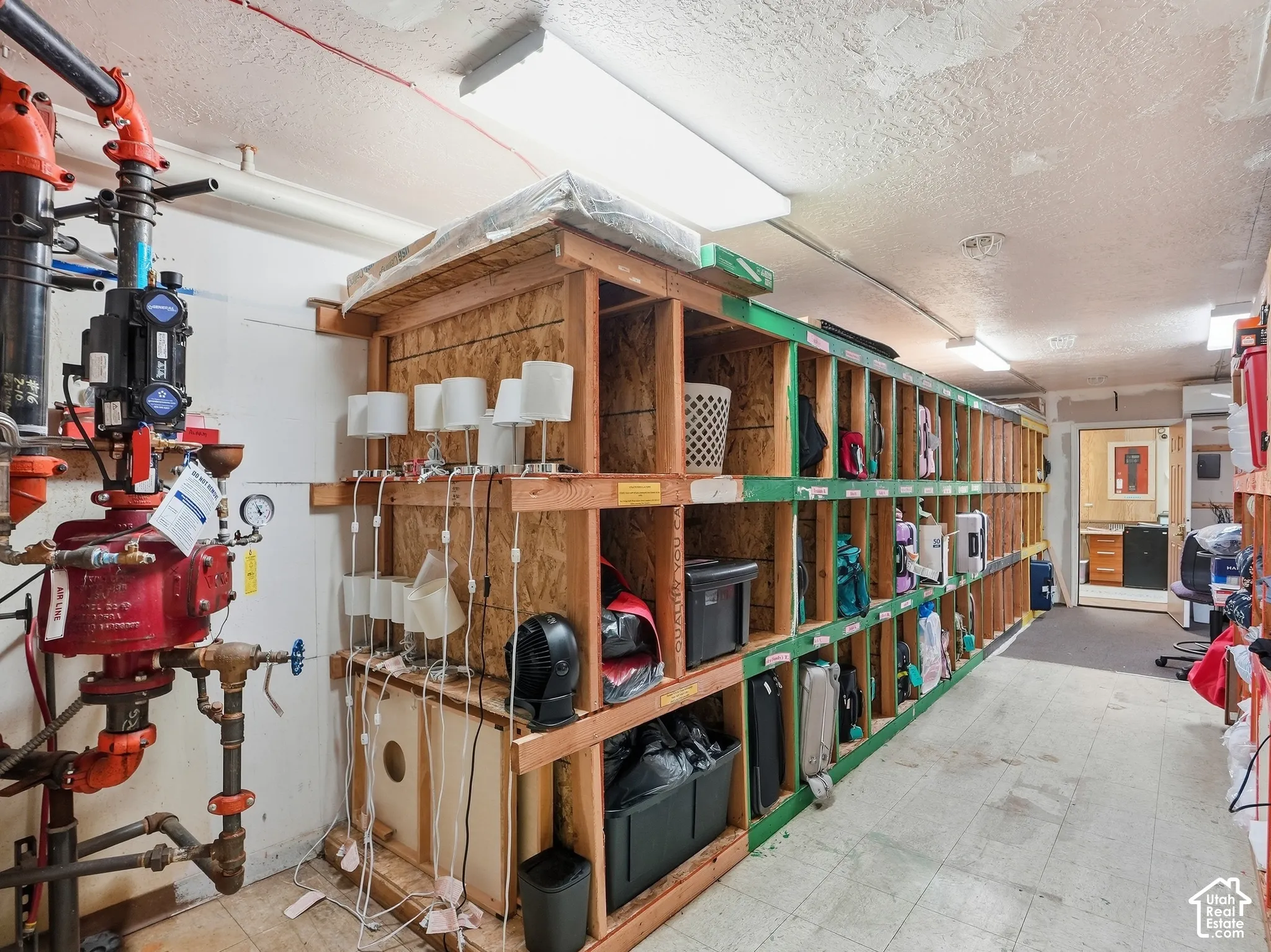 Utility room featuring extensive built-in wooden shelving, a textured ceiling, and fluorescent lighting