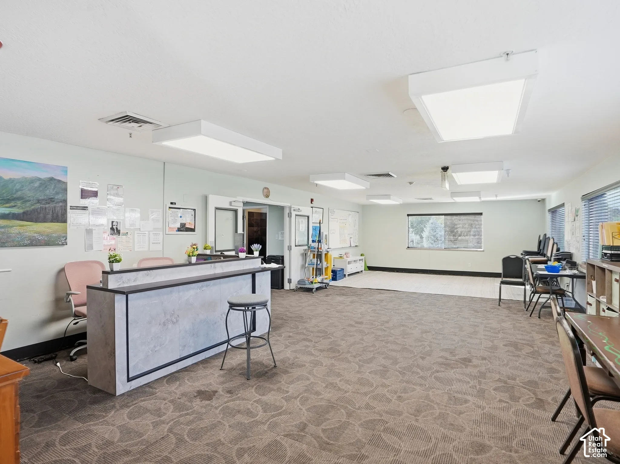 Spacious interior featuring patterned carpeting, recessed lighting, and multiple windows with blinds