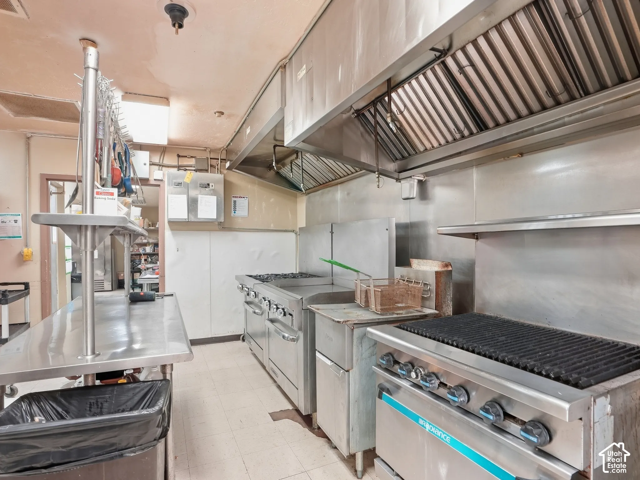 Commercial kitchen featuring stainless steel appliances, extensive stainless steel countertops, and a large commercial exhaust hood