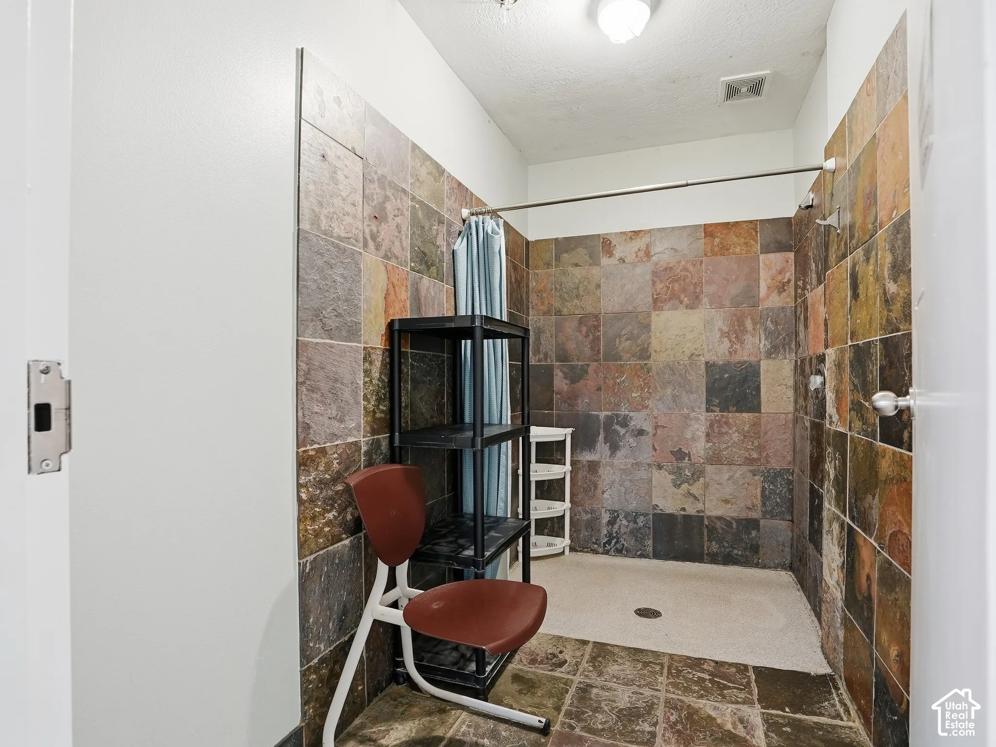 Shower with multicolored tile walls, coordinating floor tile, and a built-in shower head