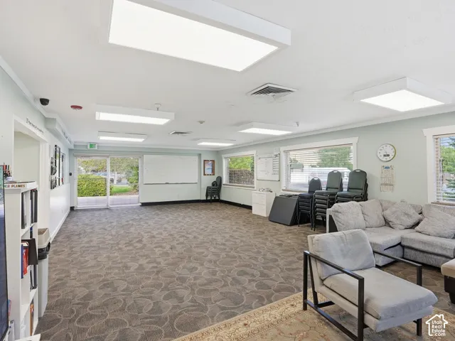 Expansive open area featuring patterned carpet flooring, multiple large windows, and recessed lighting fixtures