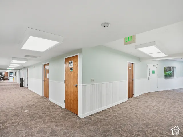 Corridor featuring patterned carpet, wainscoting, and recessed lighting