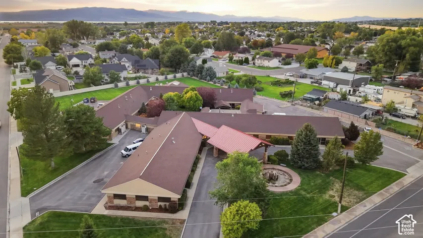 Expansive property with a brown shingle roof, stone and stucco exterior, and a red metal-roofed entryway