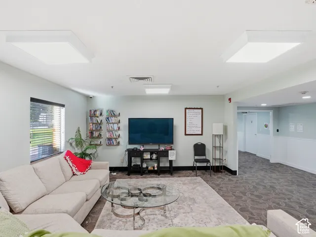Spacious interior featuring recessed lighting, a large window with horizontal blinds, and patterned carpeting