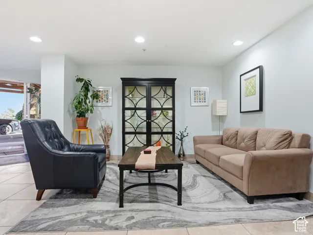 Recessed ceiling lighting, light-toned wall paint, tiled flooring, and a decorative cabinet with glass-front doors