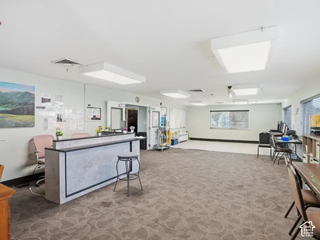 Spacious interior featuring patterned carpeting, recessed lighting, and multiple windows with blinds