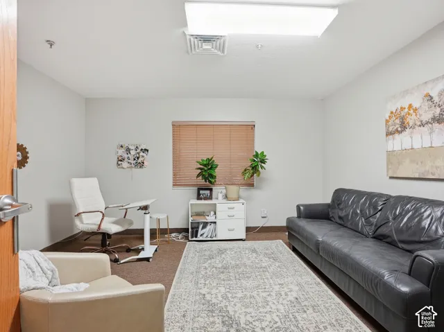 Recessed ceiling lighting, light neutral wall paint, window with horizontal blinds, wood-finish door, and carpet flooring