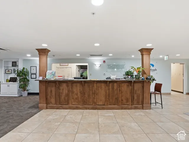 Wood-finish reception desk with integrated columns, recessed lighting, and tile flooring