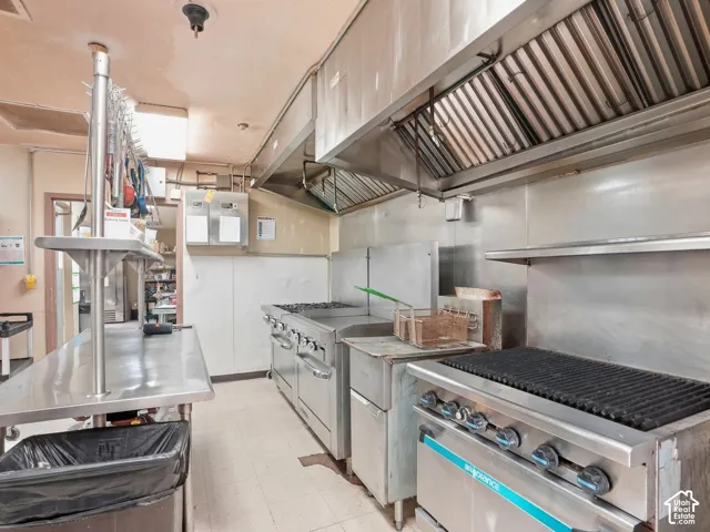 Commercial kitchen featuring stainless steel appliances, extensive stainless steel countertops, and a large commercial exhaust hood