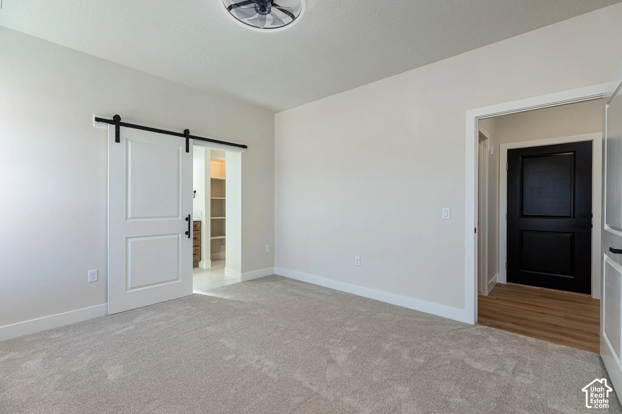 Barn door with black hardware, recessed lighting, ceiling fan, carpeted flooring, and light-toned walls