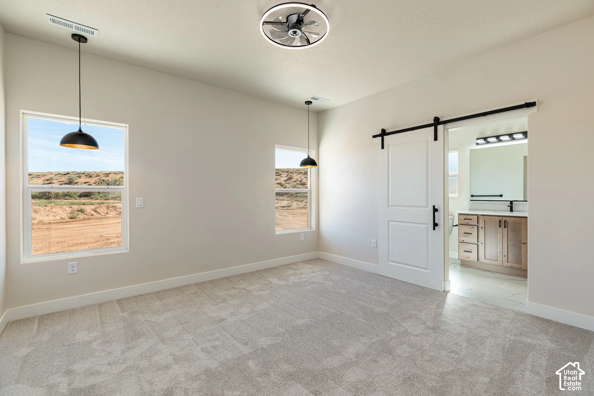 Recessed ceiling fan with integrated lighting, two pendant lights, dual windows, carpeted flooring, and a white barn door