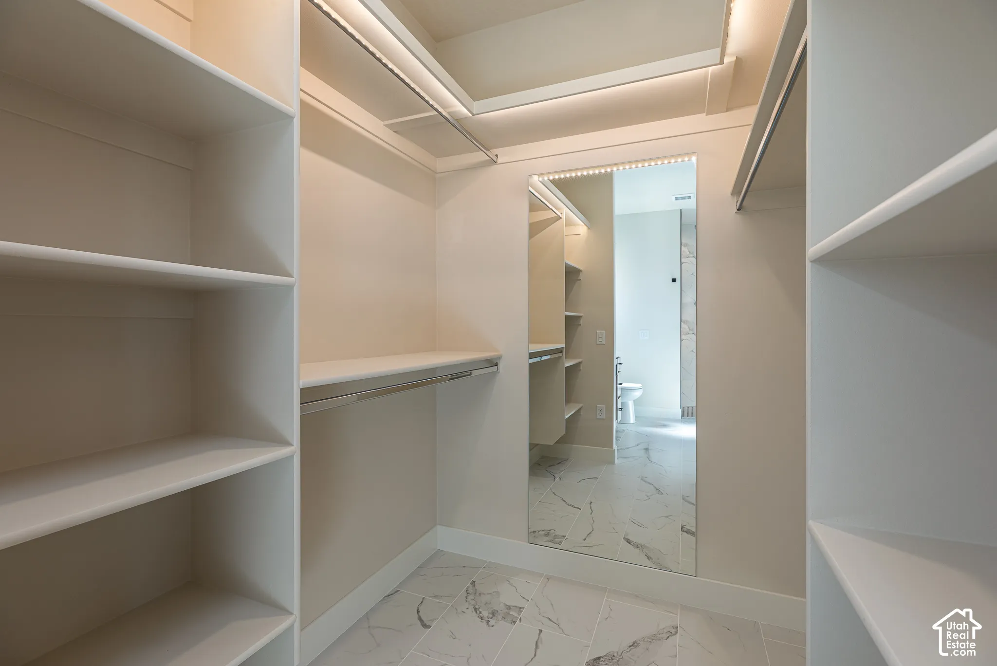 Built-in shelving, integrated hanging rods, recessed ceiling lighting, full-length mirror, and tile flooring