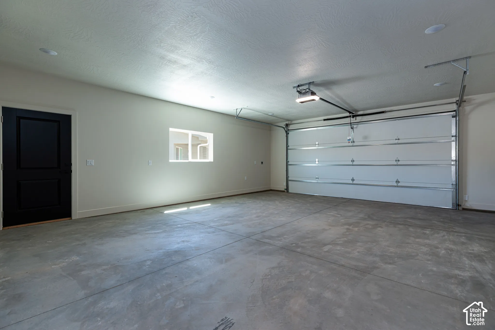Spacious garage featuring a concrete floor, automated garage door, and recessed lighting