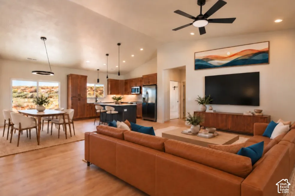 Vaulted ceiling with a ceiling fan, recessed lighting, wood-finish flooring, and a kitchen featuring wood cabinetry and an island with bar seating