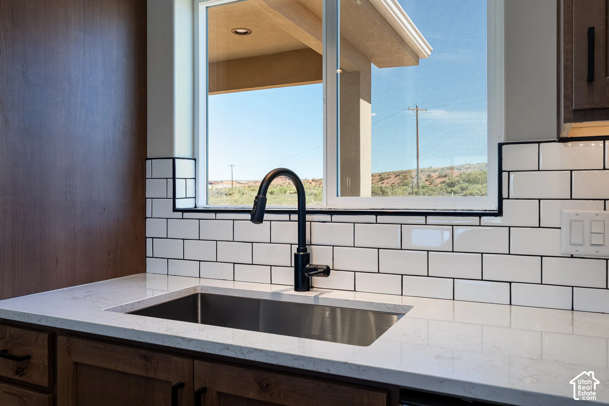 Stainless steel sink with a matte black gooseneck faucet, set within a light-toned countertop