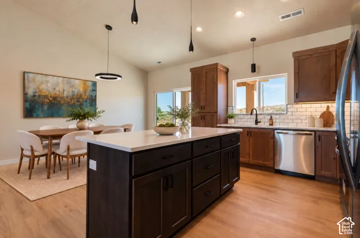 Vaulted ceilings, wood-finish flooring, dark wood cabinetry, white subway tile backsplash, and stainless steel appliances