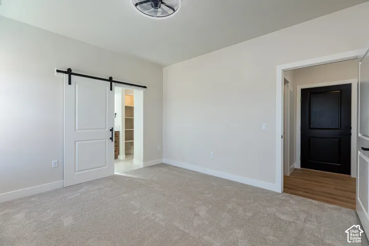 Barn door with black hardware, recessed lighting, ceiling fan, carpeted flooring, and light-toned walls