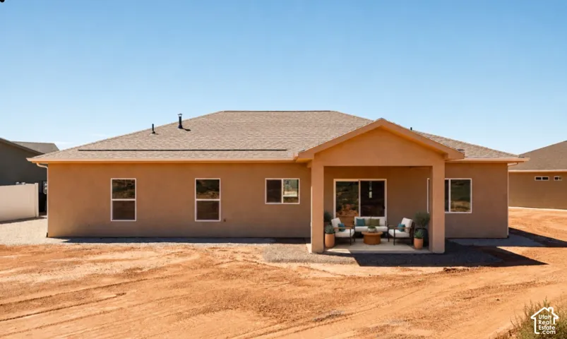 Stucco exterior with a covered patio, large yard, sliding glass door, and multiple windows