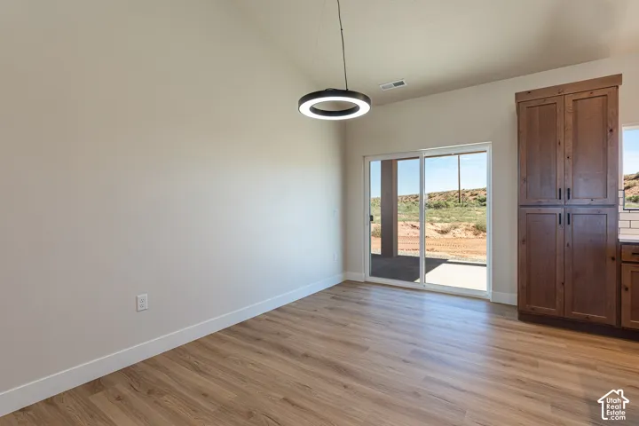 Wood-finish flooring with a modern circular pendant light, sliding glass doors, built-in cabinetry, and a white subway tile backsplash
