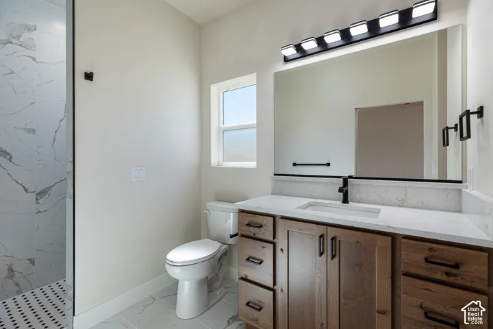 Walk-in shower with vertical tile work, vanity with integrated sink, wood-finish cabinetry, and a large mirror with contemporary lighting
