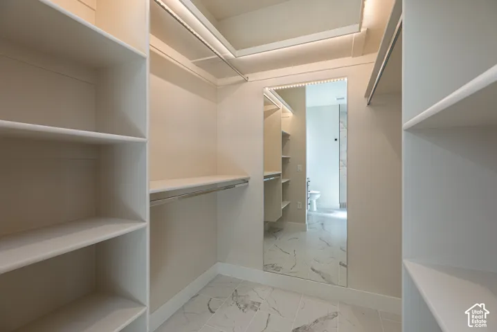 Built-in shelving, integrated hanging rods, recessed ceiling lighting, full-length mirror, and tile flooring