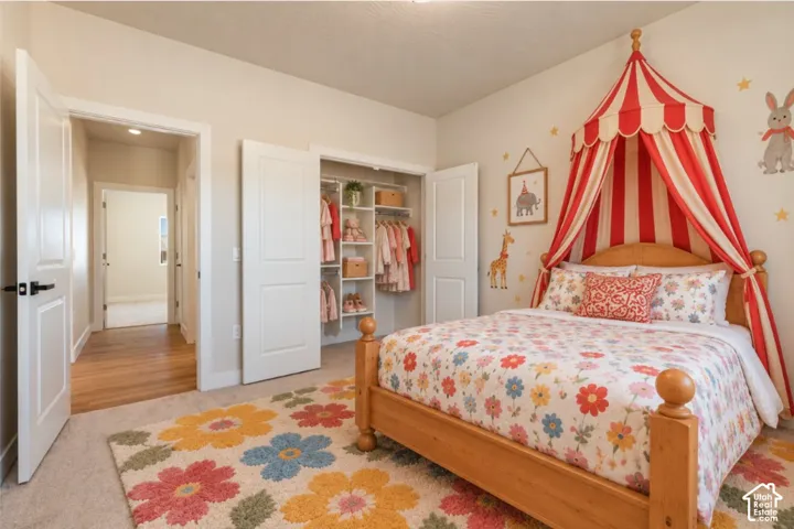 Built-in closet with shelving, two-panel interior doors, light-colored carpeting, and wood-finish flooring in the hallway