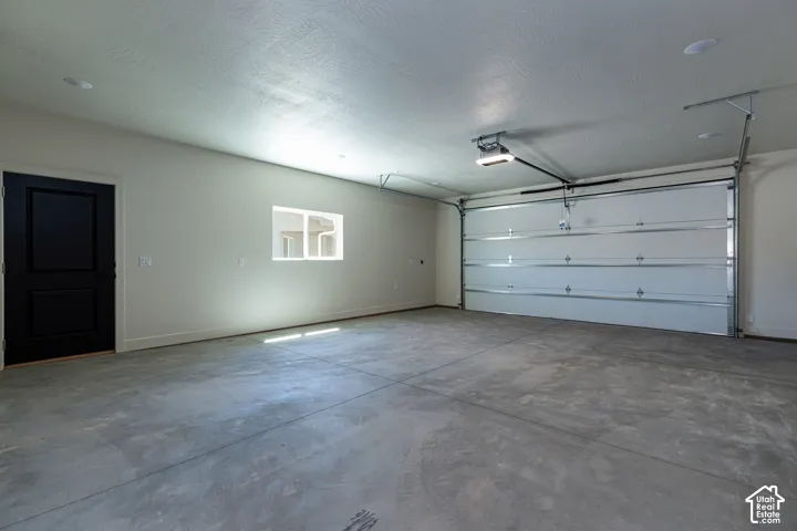 Spacious garage featuring a concrete floor, automated garage door, and recessed lighting