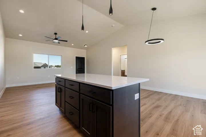 Open-concept living space featuring wood-finish flooring, a vaulted ceiling, and recessed lighting