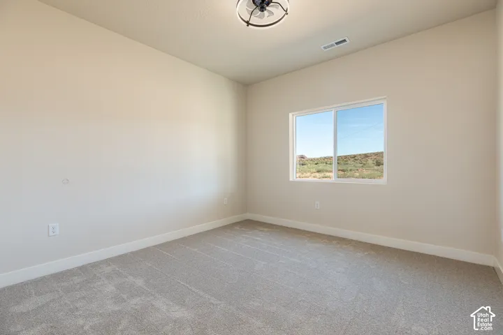 Neutral tone walls, carpeted flooring, window with natural scenery, and a ceiling-mounted light fixture