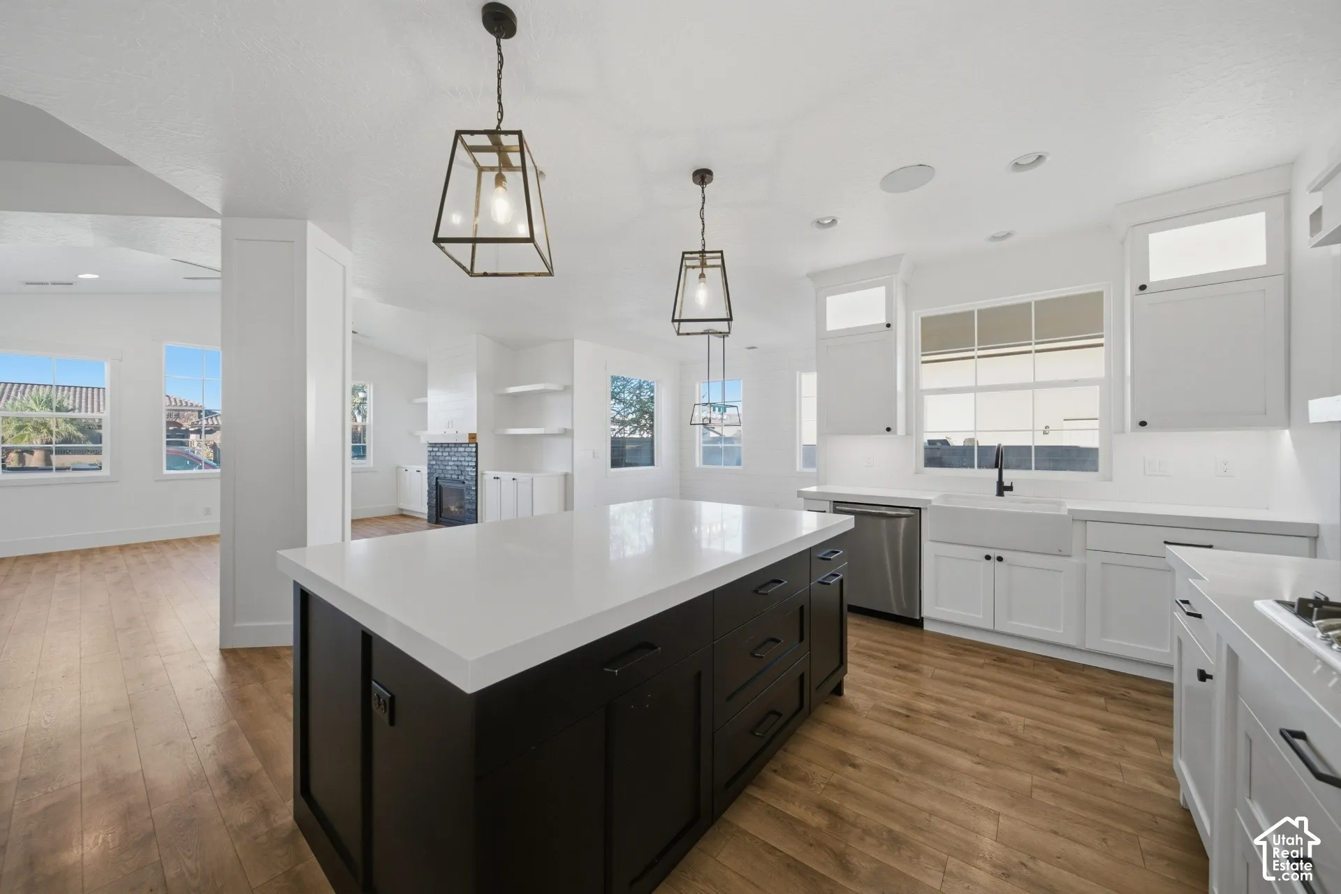 Kitchen featuring a black island with a white countertop, white cabinetry, stainless steel appliances, and wood-finish flooring