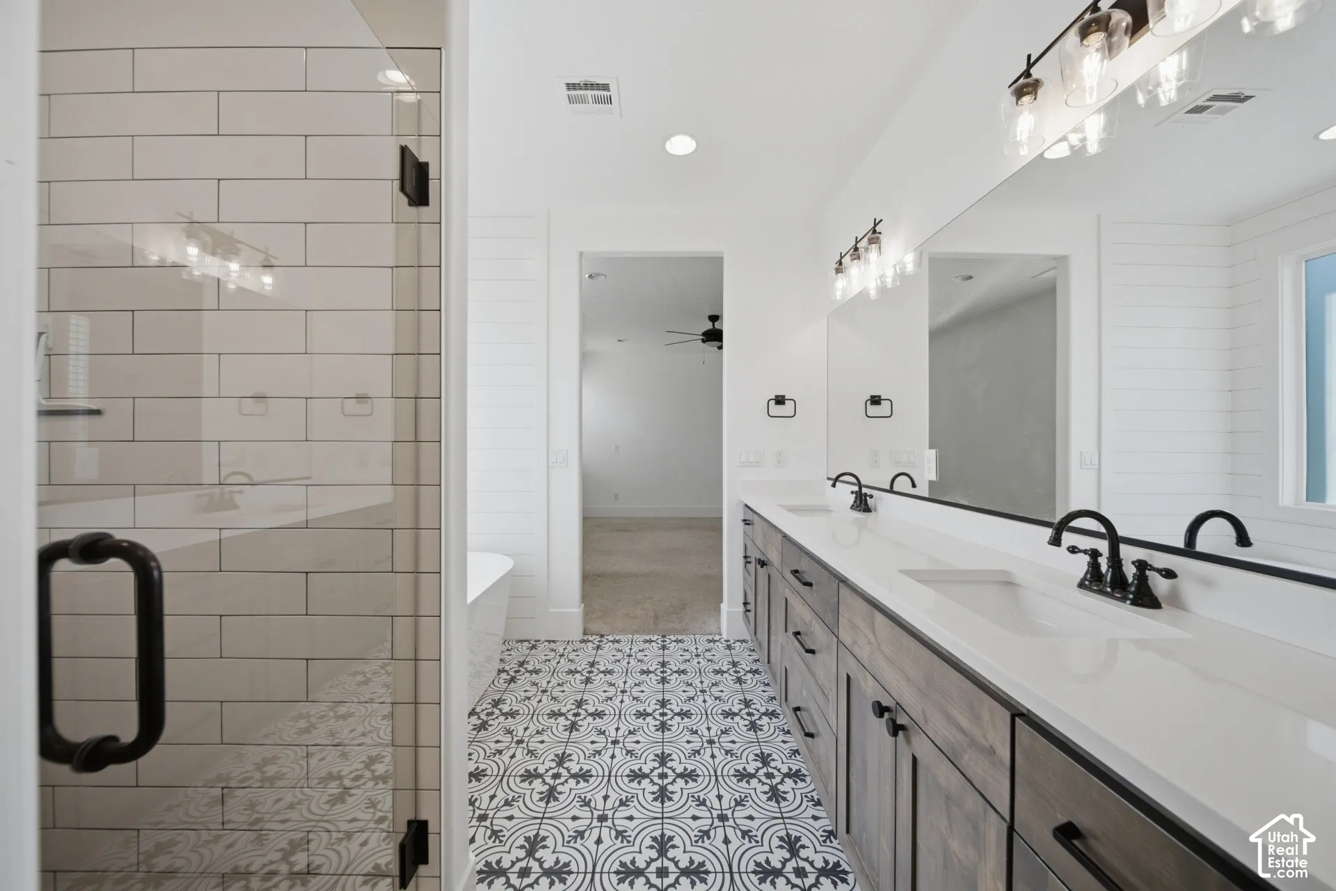 Dual sink vanity with dark wood-finish cabinetry, white countertops, and matte black fixtures
